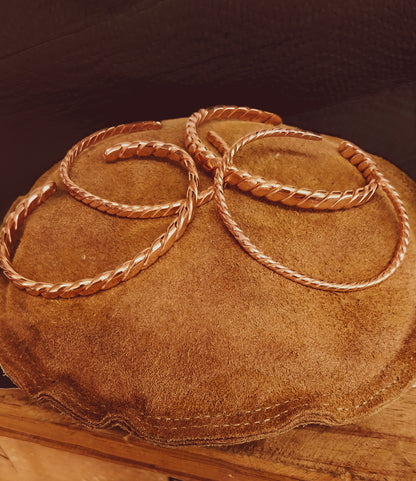 Four twisted rope-style cuff bracelets, hand forged in copper.